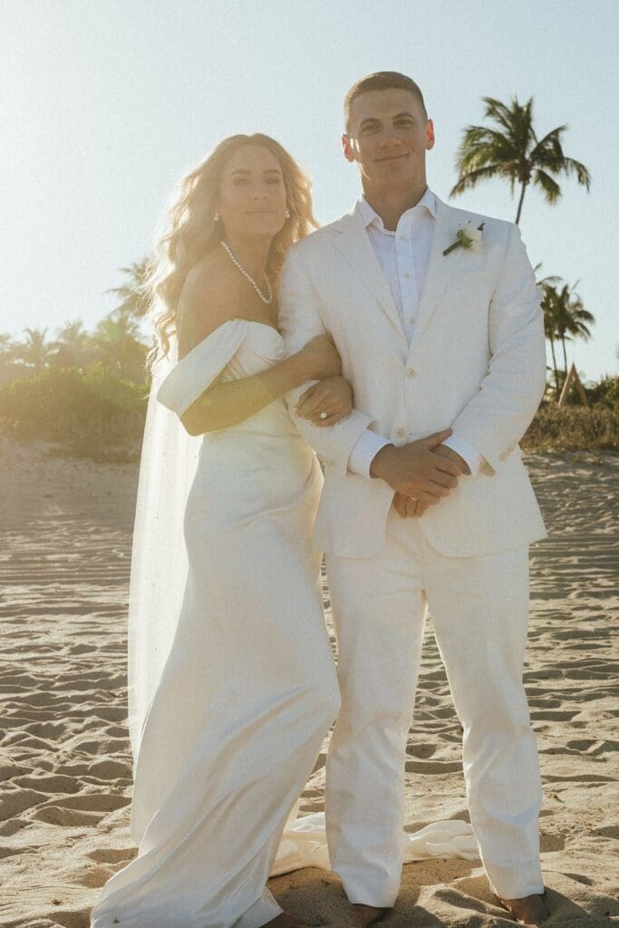 bride and groom posing on the beach for destination wedding pics at sunset